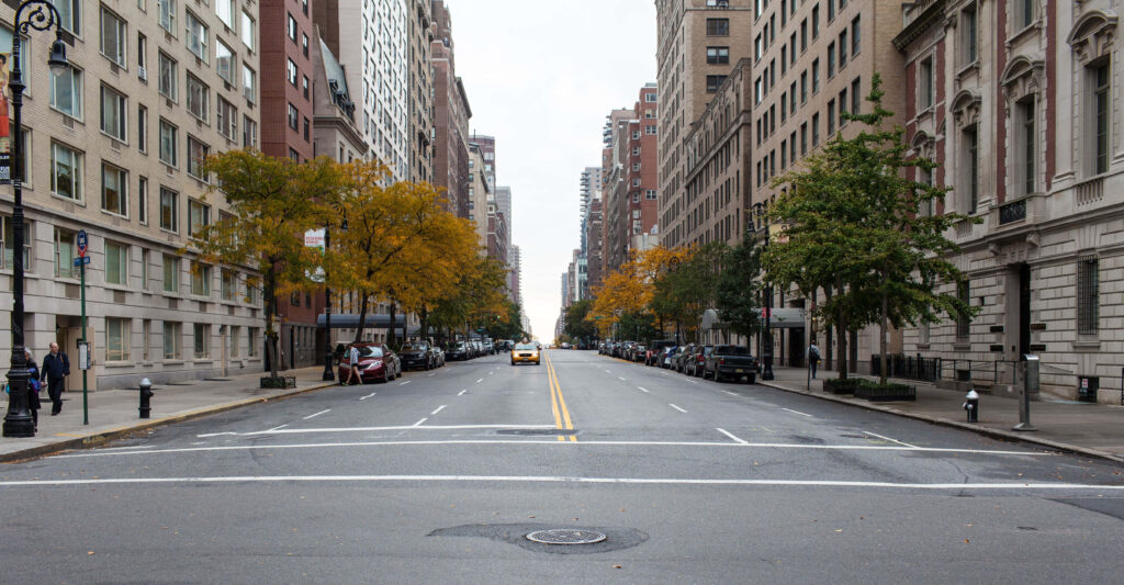 Vibrant Urban Street Scene: Autumn Trees & Towering Buildings Wallpaper
