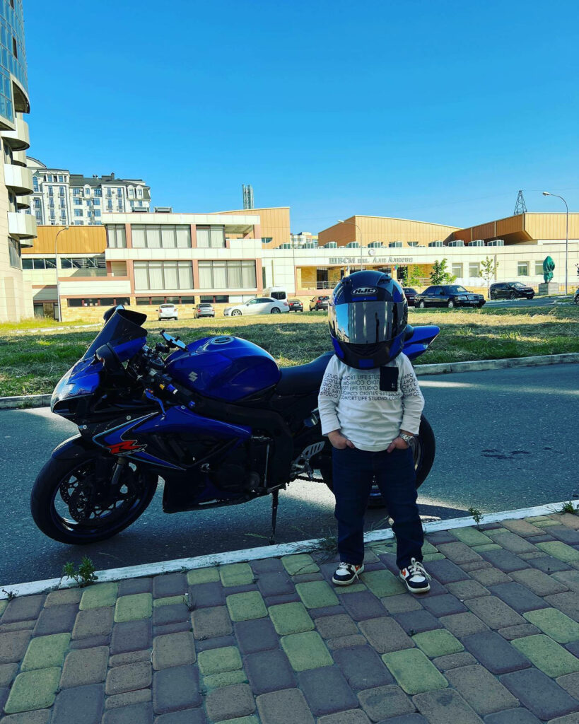 Playful Wallpaper: Person with Oversized Helmet & Blue Motorcycle