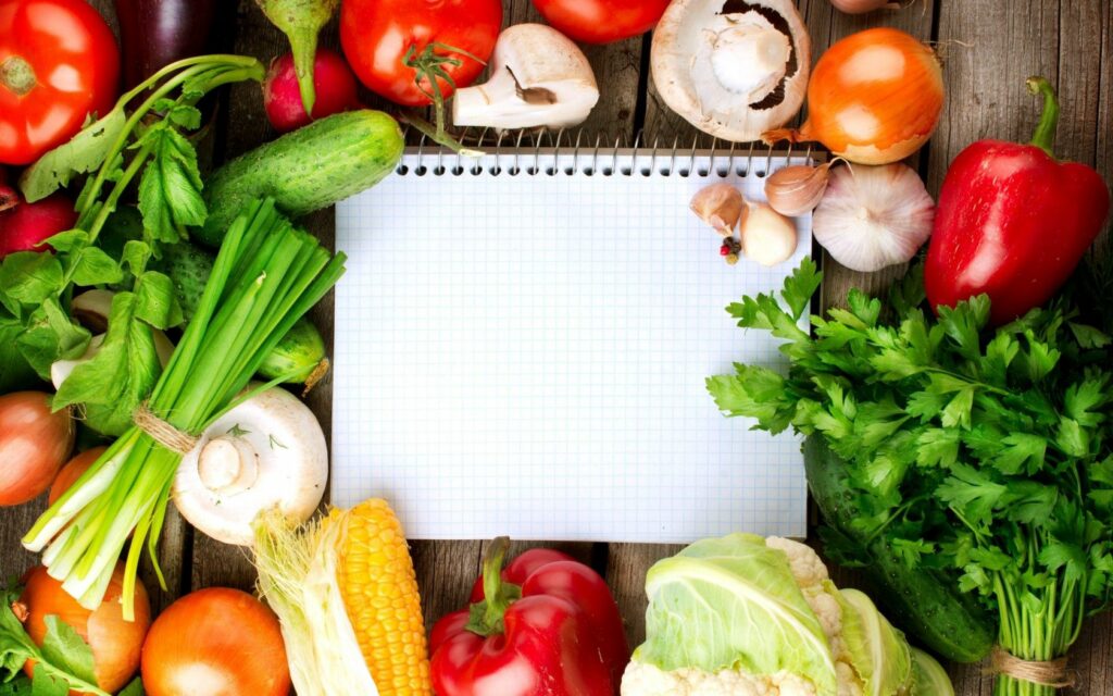 Vibrant Vegetable Wallpaper with Blank Notebook on Rustic Background