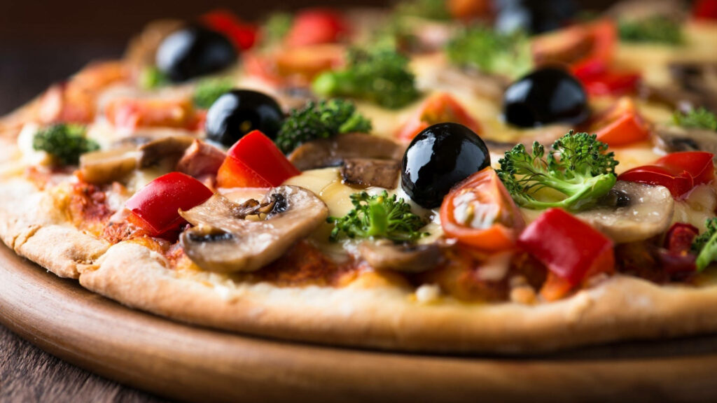 Close-up of colorful vegetable pizza with broccoli mushrooms red peppers olives on crispy crust Wallpaper
