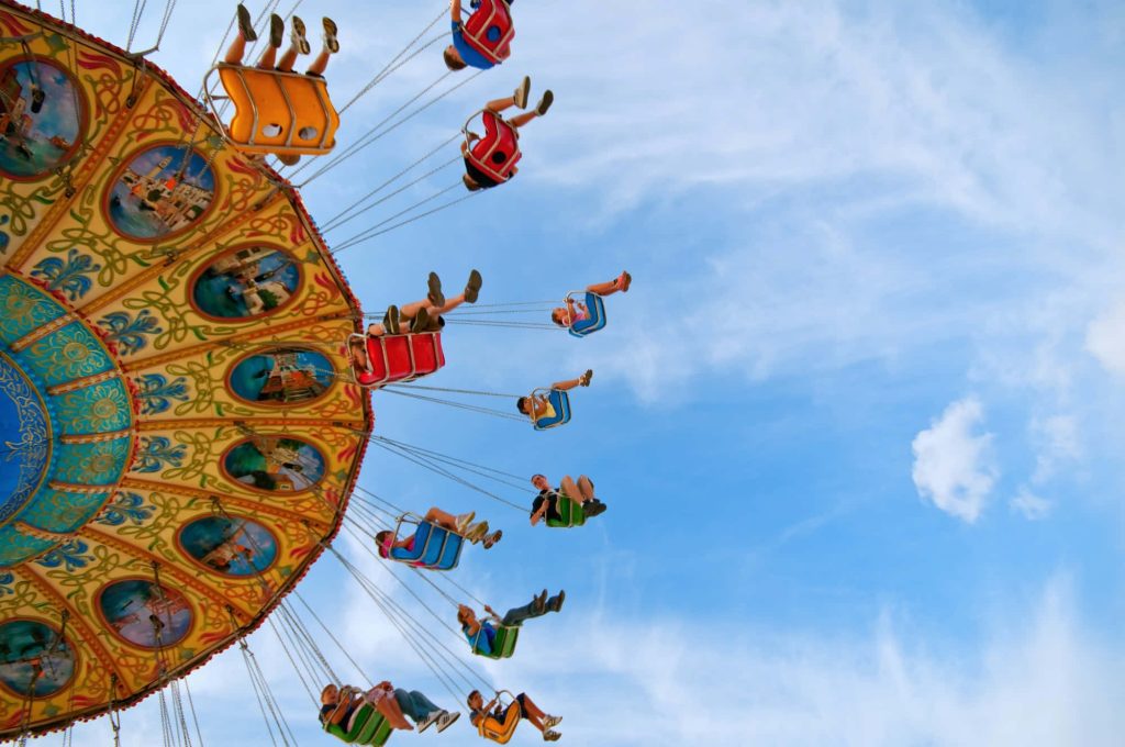 Vibrant vintage amusement park swing ride with people soaring under clear blue sky summer fun Wallpaper