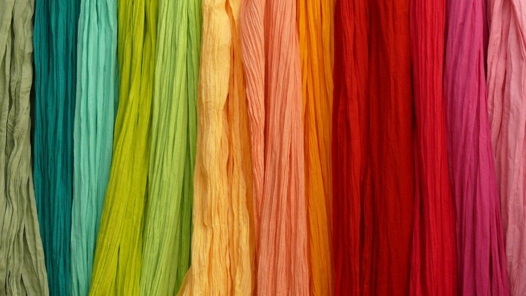 Vibrant rainbow crinkled fabric strips textured wallpaper background with smooth colorful gradient