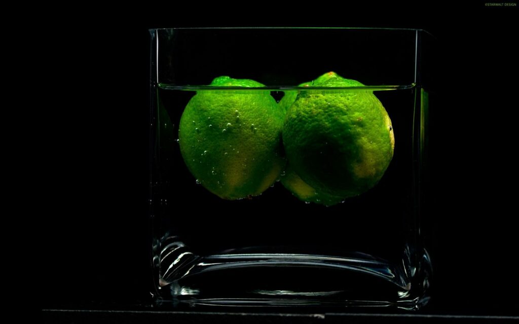 Vibrant Wallpaper of Fresh Limes in Water on Dark Background
