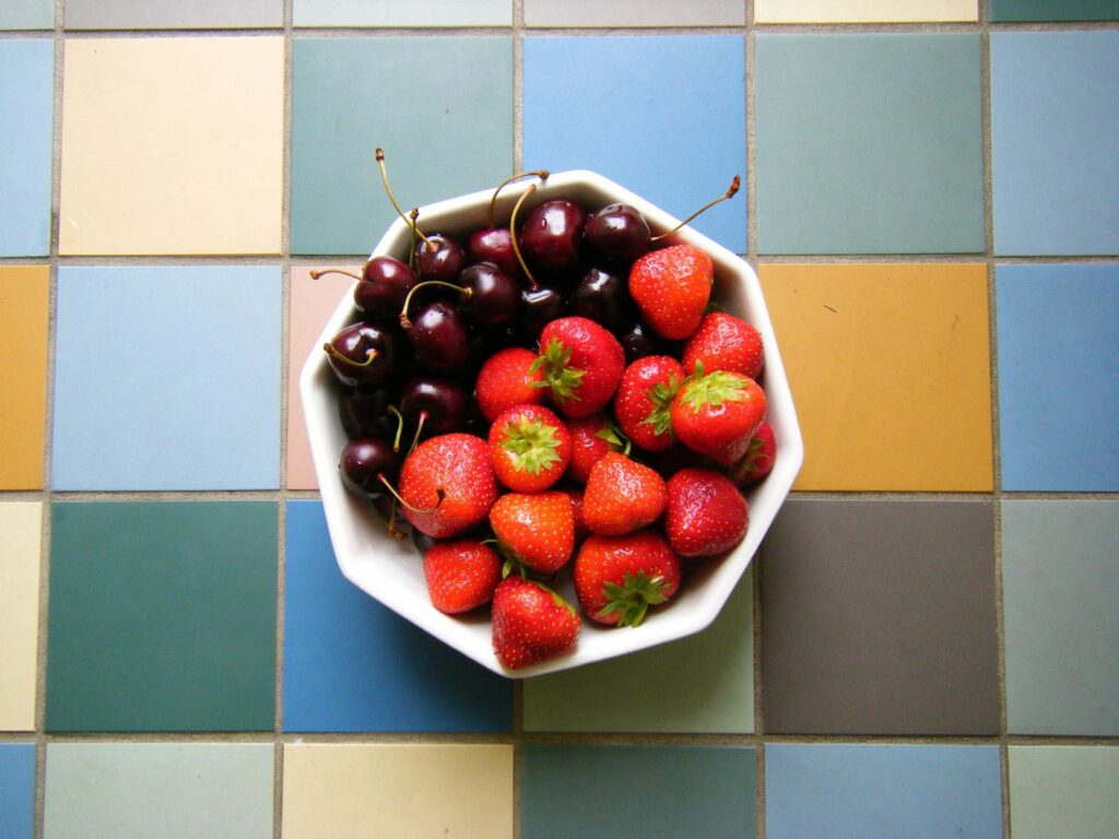 Vibrant Wallpaper: Bowl of Fresh Strawberries & Cherries on Colorful Tiles
