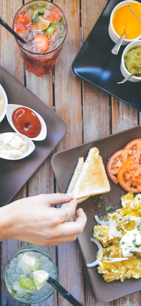 Vibrant Wallpaper: Hand Reaching for Delicious Breakfast on Wood Table