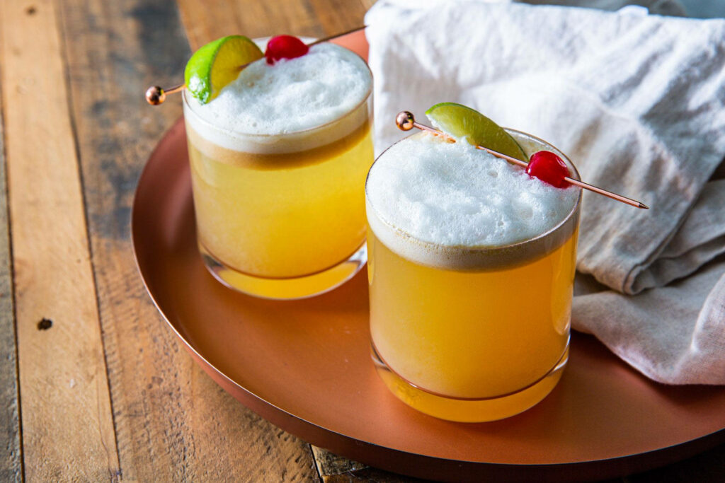 Vibrant Whiskey Sour Cocktails Wallpaper on Rustic Wood Surface