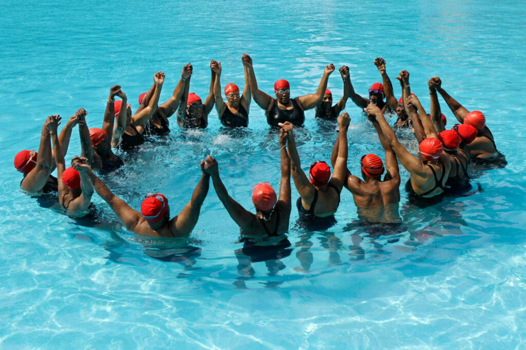 Vibrant Teamwork Wallpaper: Synchronized Swimmers in Clear Blue Pool