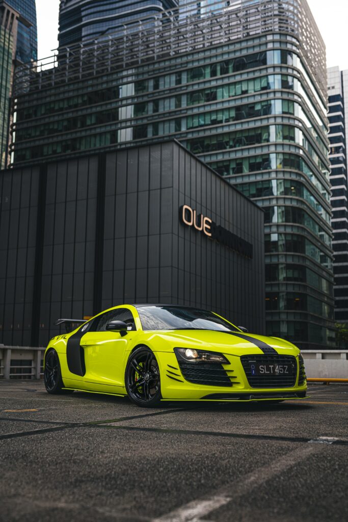 Vibrant Yellow Audi R8 Sport Car Amid Urban Cityscape Wallpaper