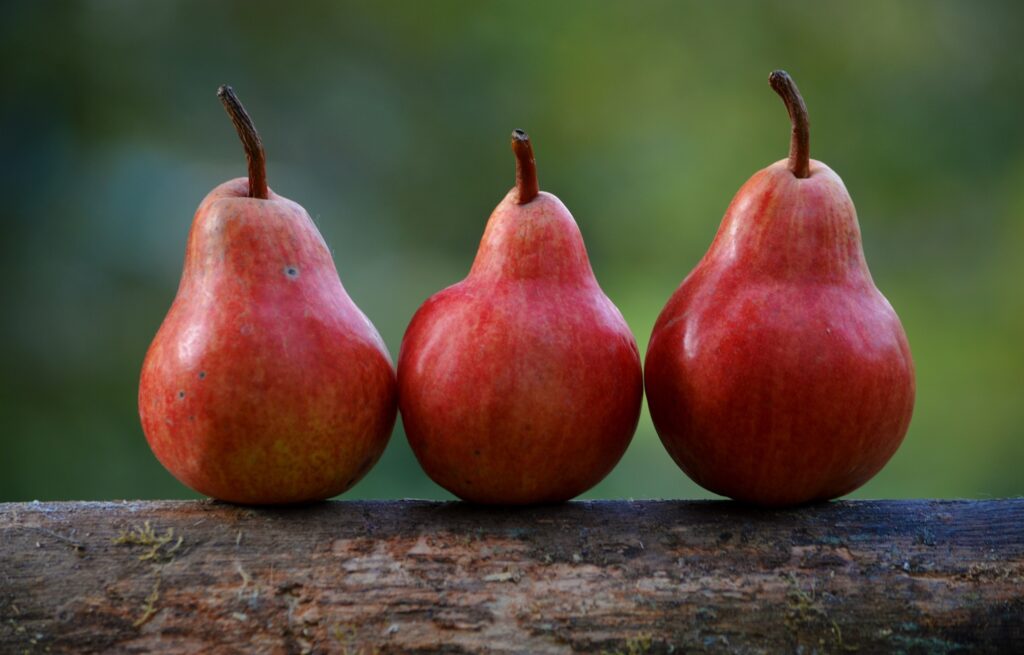 Vibrant Wallpaper: Ripe Red Pears on Rustic Wood with Green Blur