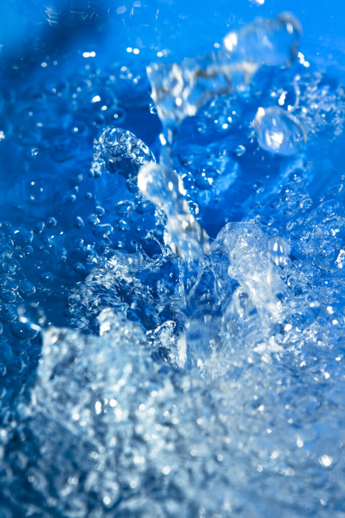 Dynamic Water Splash Wallpaper: Vibrant Close-Up on Blue Background