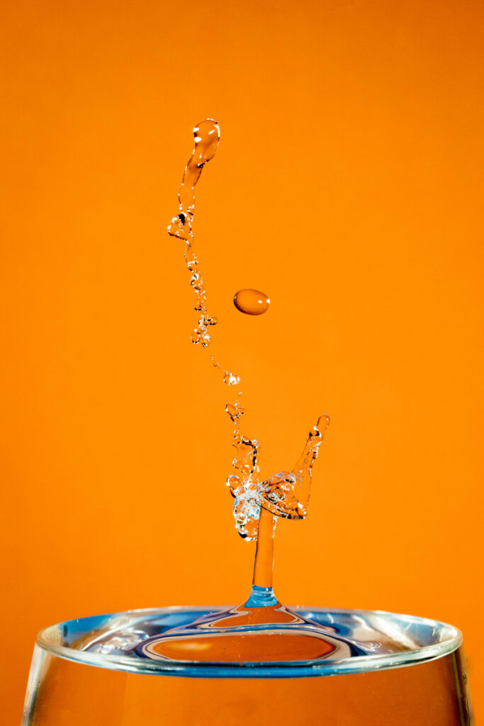 Vibrant Water Splash Macro Shot - Intricate Drops on Orange Wallpaper