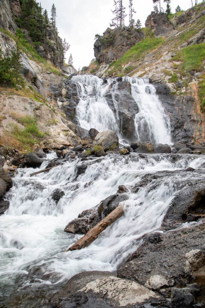 Vibrant waterfall cascading over rugged rocks surrounded by lush green forest natural wallpaper