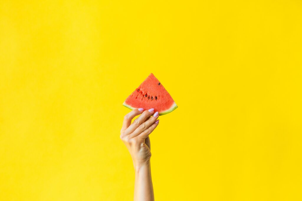Vibrant Wallpaper: Hand Holding Juicy Watermelon on Yellow Background