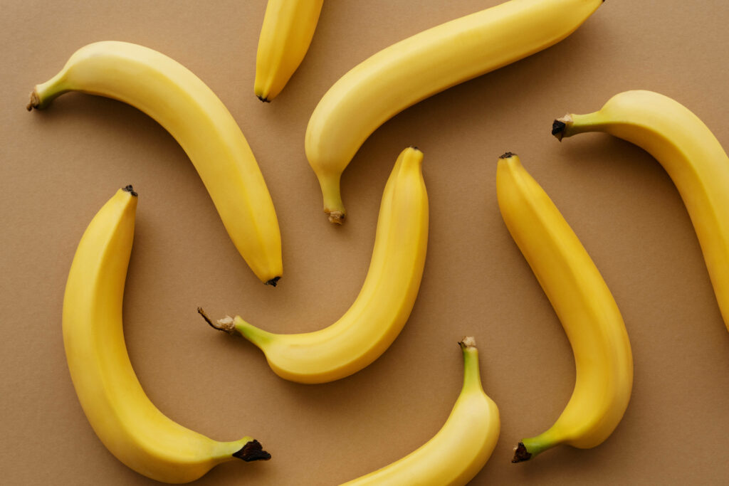 Vibrant yellow bananas scattered on soft brown background playful tropical wallpaper design