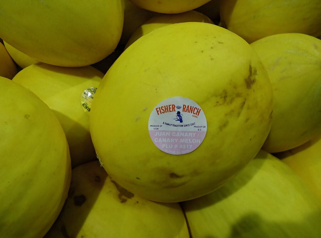 Close-up of vibrant yellow canary melons cluster with smooth texture and authentic label wallpaper