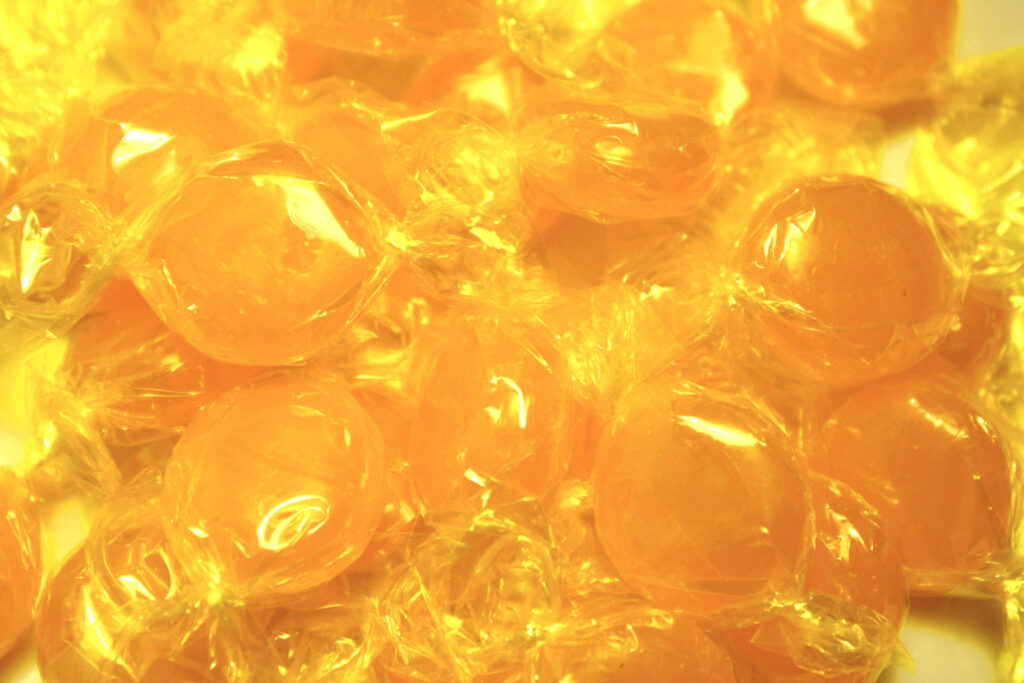 Close up of glossy wrapped yellow candies bright cheerful wallpaper background for laptop
