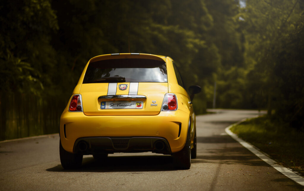 Vibrant Yellow Car on Scenic Road - Stylish Automotive Wallpaper