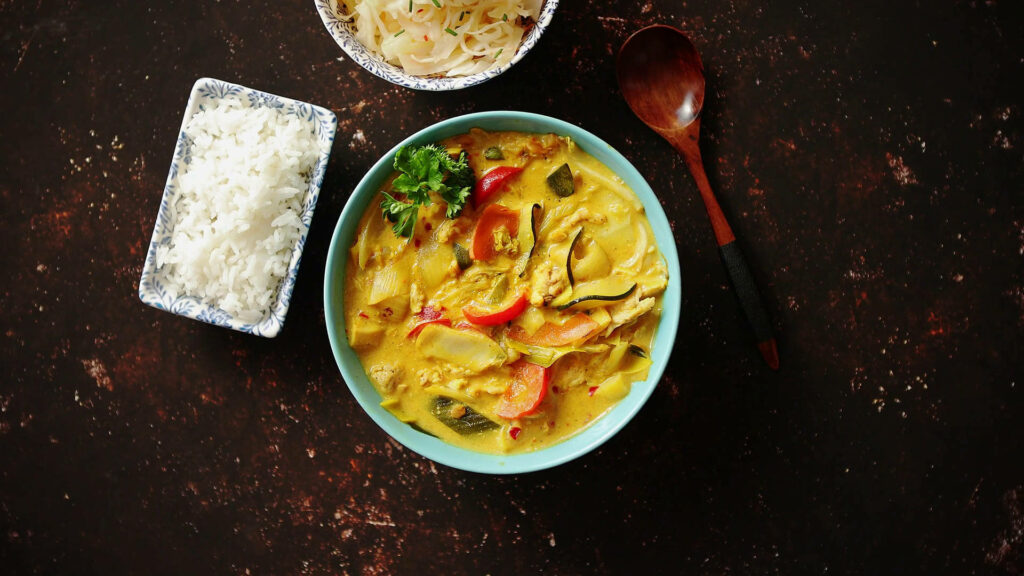 Vibrant Yellow Curry Wallpaper: Noodles & Rice on Rustic Background
