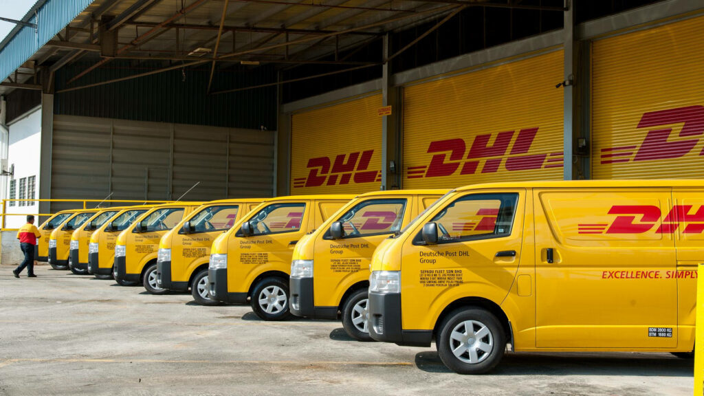 Fleet of bright yellow DHL Express vans with red logos parked outside warehouse for global logistics Wallpaper