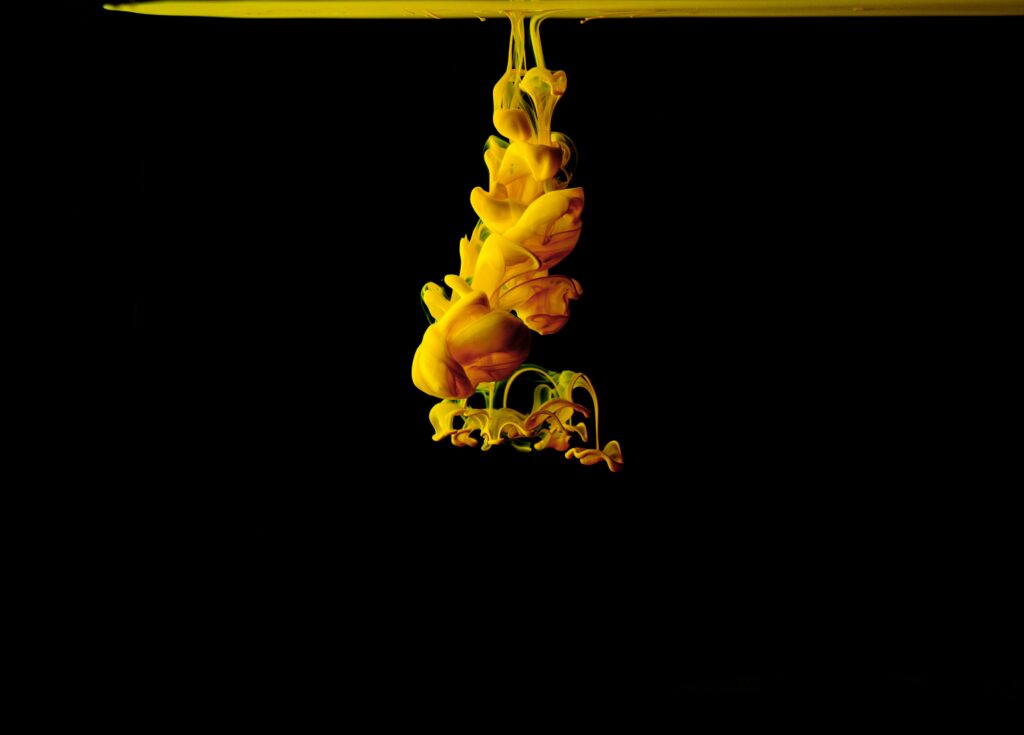 Vibrant Yellow Ink Macro Wallpaper: Fluid Swirls on Dark Background