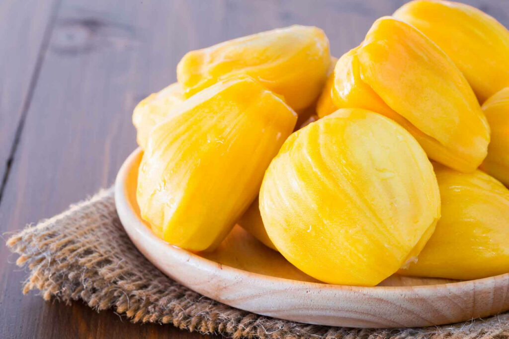 Vibrant Yellow Ripe Jackfruit Flesh on Wooden Plate - Juicy Wallpaper