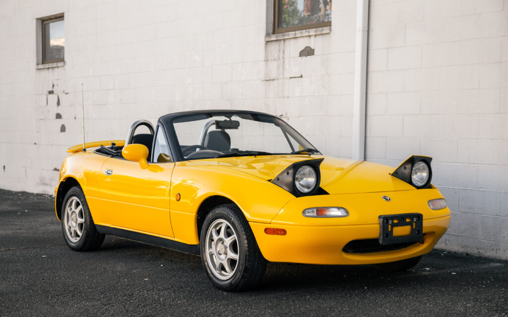 Vibrant Yellow Mazda MX-5 Against Minimalist Concrete Wall Background Wallpaper