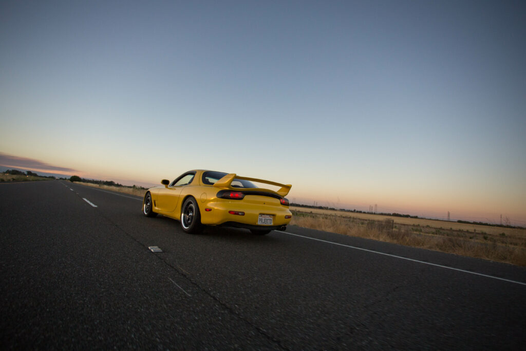 Vibrant Mazda RX-7 at Sunset: Speed and Beauty on Open Road Wallpaper