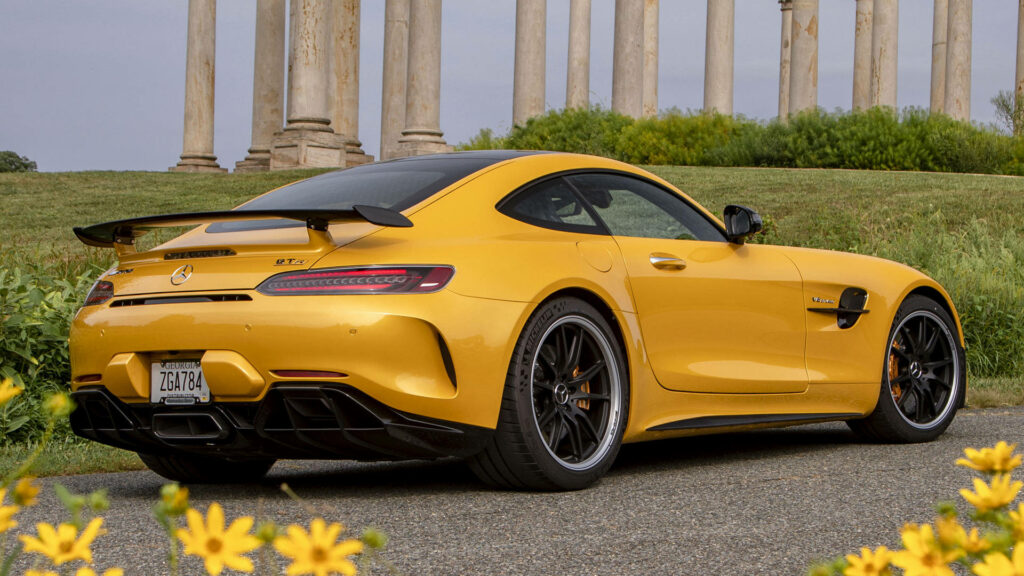 Yellow Mercedes AMG GT R parked on scenic road with lush greenery and classic columns background Wallpaper