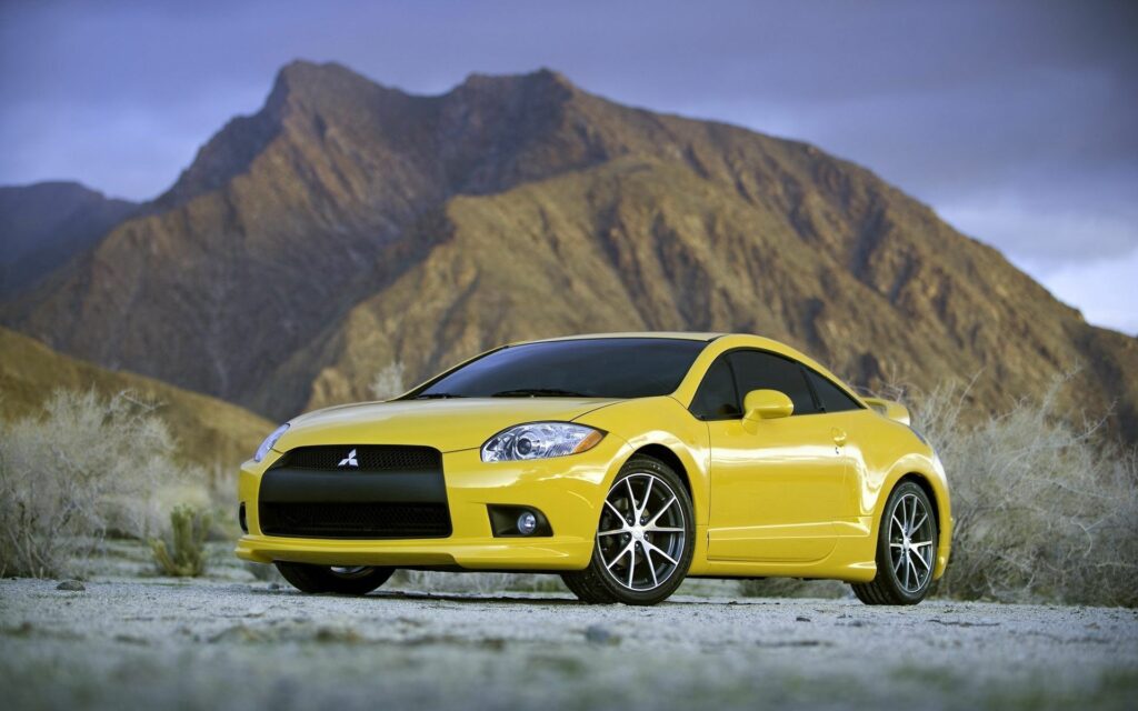 Vibrant Yellow Mitsubishi Car with Mountainous Background Wallpaper