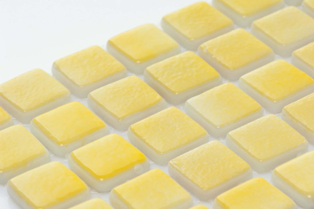 Macro photo of vibrant yellow square mosaic tile wallpaper with glossy translucent textures