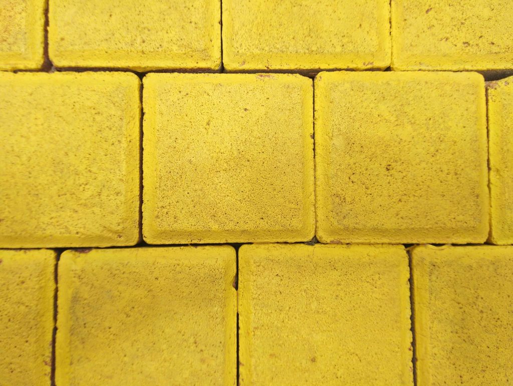 Vibrant yellow paving stones texture wallpaper with geometric grid and detailed granular surface