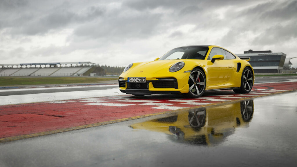 Vibrant Yellow Porsche 911 Wallpaper: Sleek Wet Track Reflection