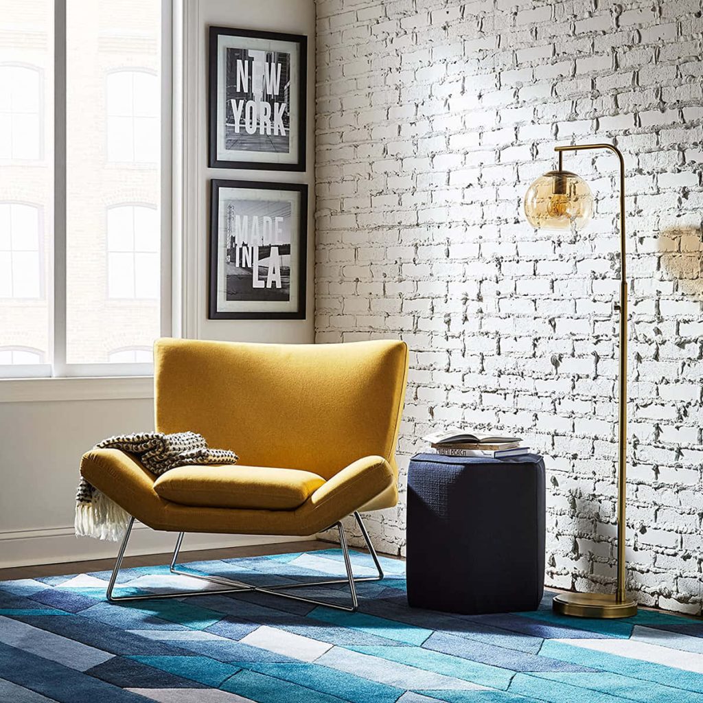 Yellow Rivet Farr Lotus accent chair in modern reading nook with gold lamp and blue rug Wallpaper