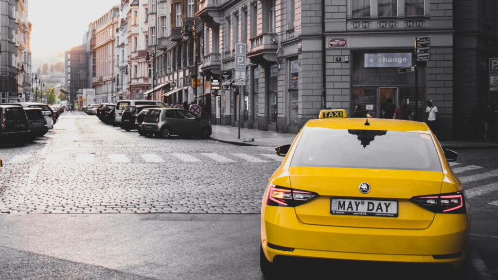 Historic Urban Yellow Taxi Mid-Turn: Vibrant Wallpaper Background