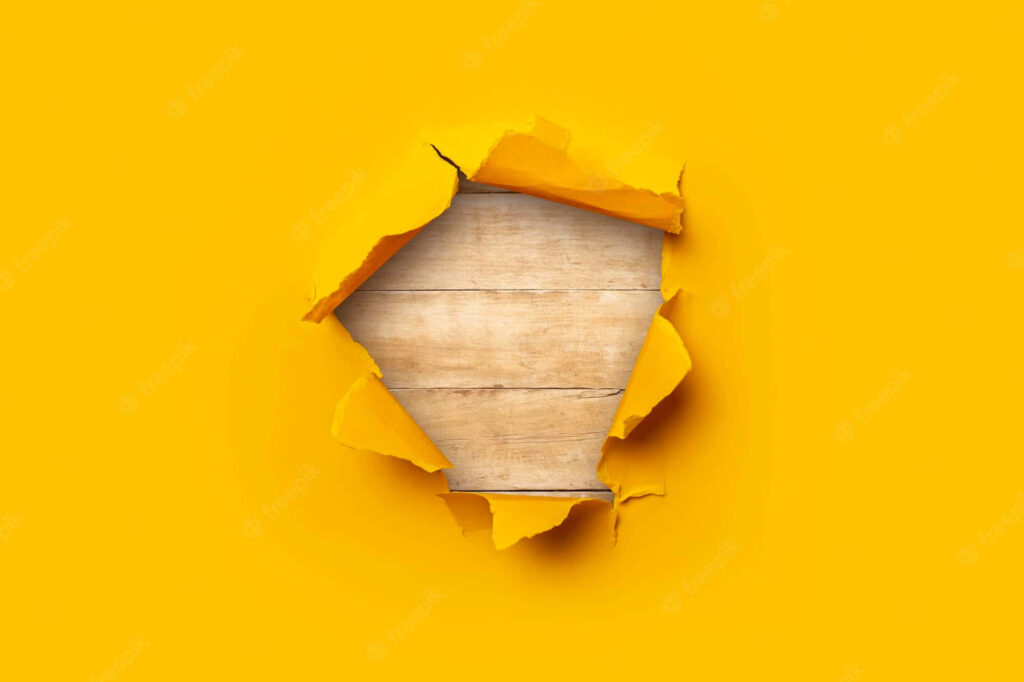 Vibrant Yellow Torn Wallpaper Revealing Wooden Texture Background