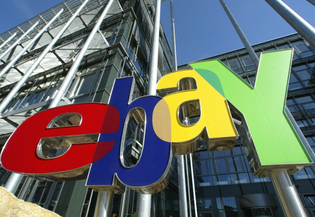 Vibrant eBay logo in red blue yellow green on modern glass office building with clear blue sky background Wallpaper