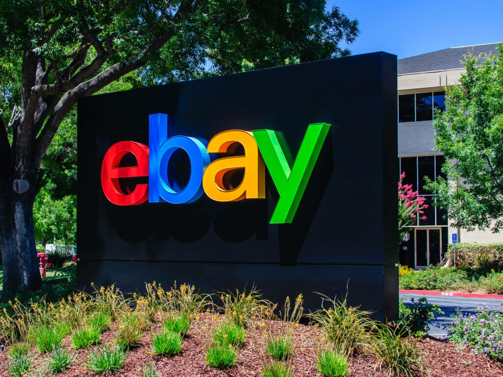 Vibrant eBay logo wallpaper with lush greenery and modern office architecture background