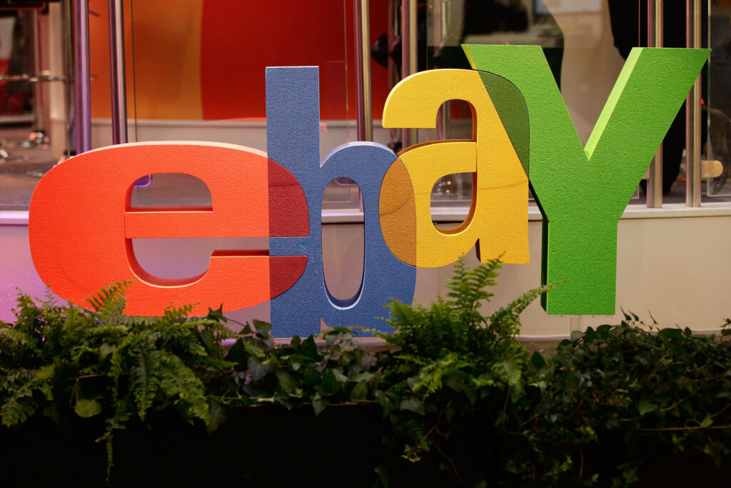 eBay logo wallpaper with vibrant colors on sleek indoor backdrop featuring glass panels and greenery