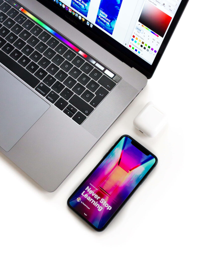 Vibrant iPhone with colorful inspiring message screen on white desk near laptop and earbuds Wallpaper