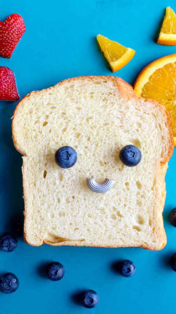 Cheerful iPhone Wallpaper: Smiling Bread Slice & Colorful Fruits
