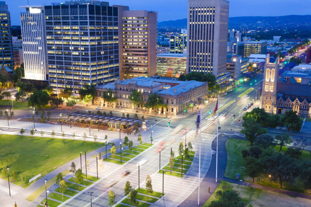 Aerial twilight view of Victoria Square Adelaide with illuminated buildings and green spaces Wallpaper