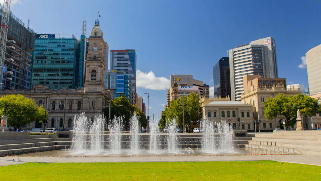 Victoria Square Fountain in Adelaide surrounded by classic and modern buildings under blue sky Wallpaper