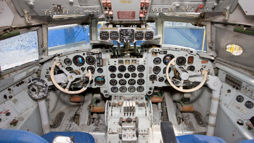 Vintage aircraft cockpit interior with analog gauges and worn control yokes wallpaper background