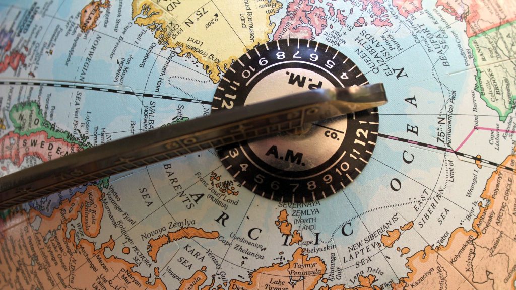 Macro photo of vintage globe Arctic map with metallic time zone indicator showing AM PM zones Wallpaper