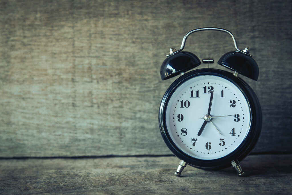 Classic black alarm clock on textured wood background vintage charm rustic minimalist wallpaper