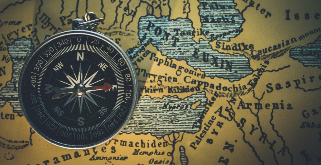 Classic black silver compass on antique vintage map background evoking exploration adventure Wallpaper