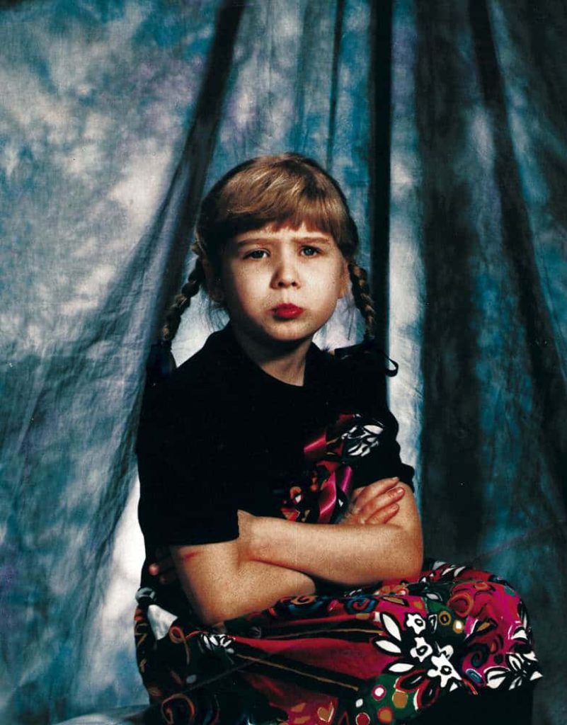 Vintage 90s style portrait of a young blonde girl with braids and a sassy pout background Wallpaper