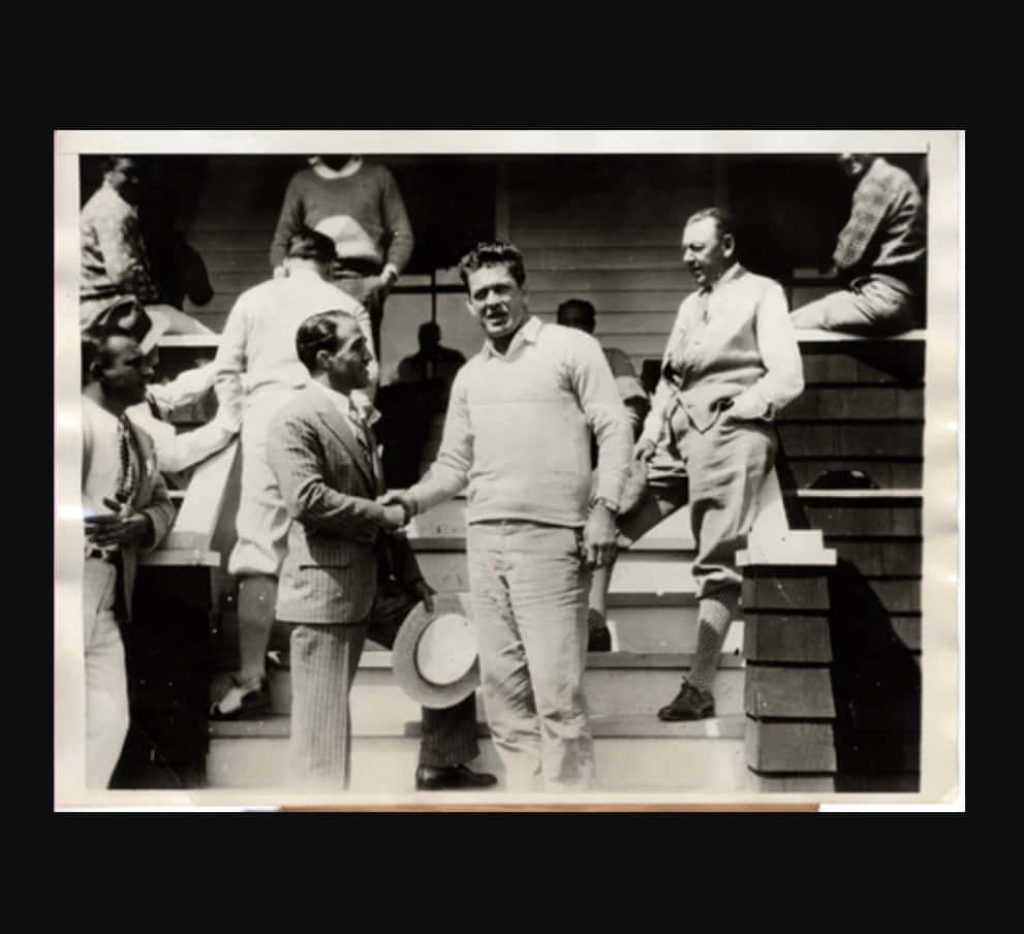 Vintage black-and-white photo of boxers Gene Tunney and Johnny Dundee shaking hands outdoors Wallpaper