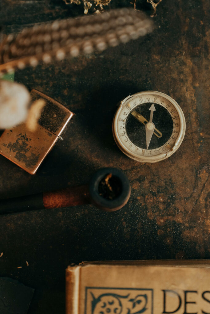 Vintage brass compass with classic pipe old lighter and antique book on rustic textured background Wallpaper