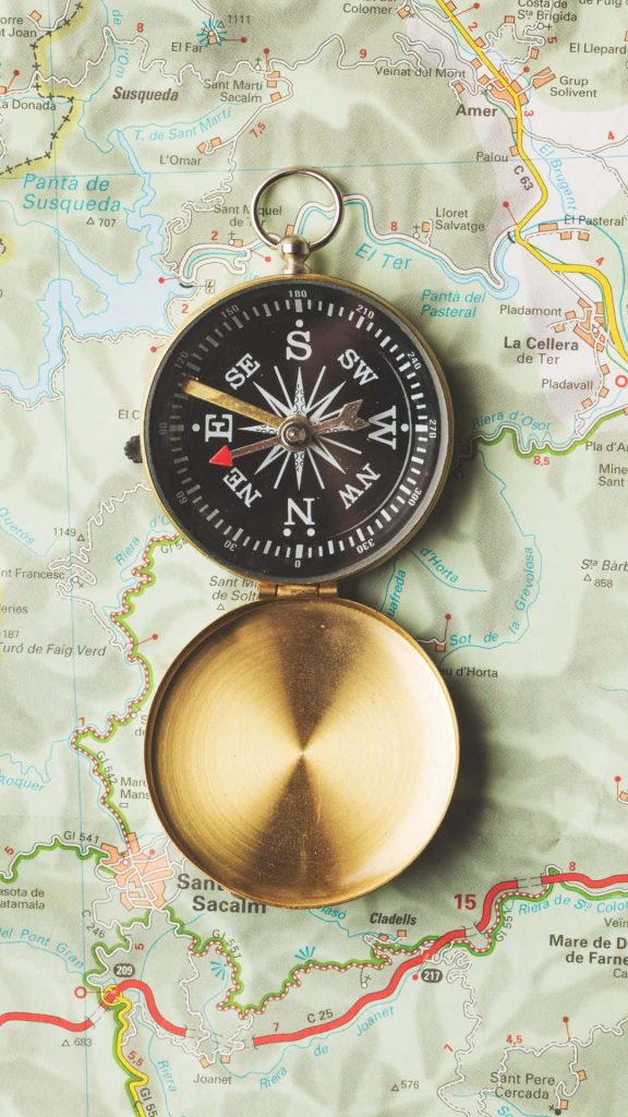 Vintage brass compass on detailed Catalonia Spain map travel wallpaper background adventure